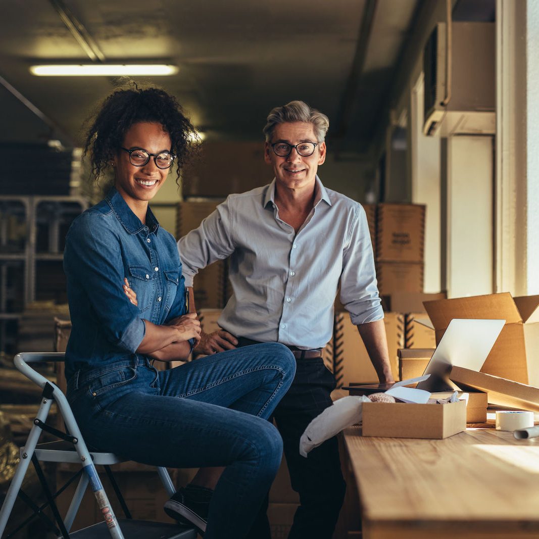 Private online business owners Portrait of man and woman standing in online store warehouse. Business partners together looking at camera and smiling.